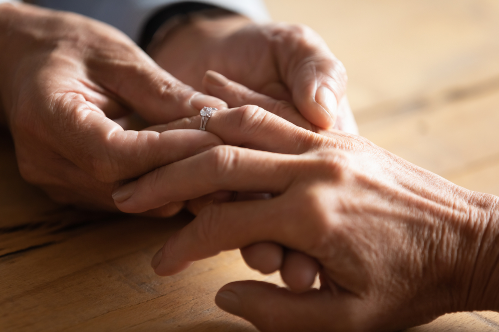 Close up elder senior man putting diamond ring on finger of middle aged woman