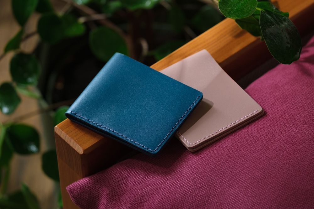 blue and pink leather wallets lying on a purple sofa indoors