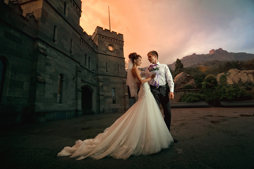 bride and groom outside an old castle in the evening for wedding pictorial