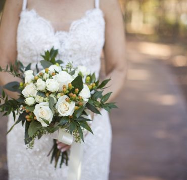 bride on white strap wedding dress holding a bouquet of flowers