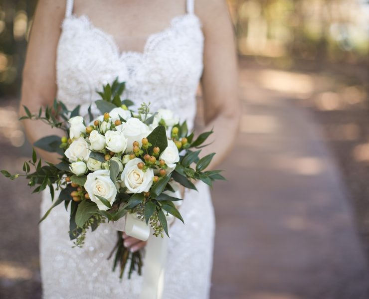 bride on white strap wedding dress holding a bouquet of flowers