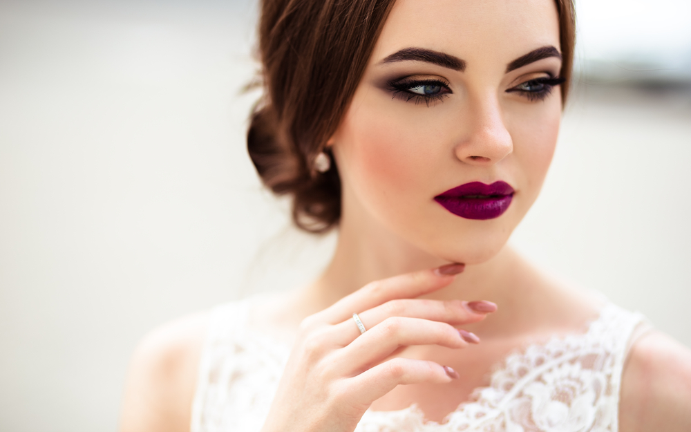 close up shot of a bride on bold dark lipstick and wearing a white dress