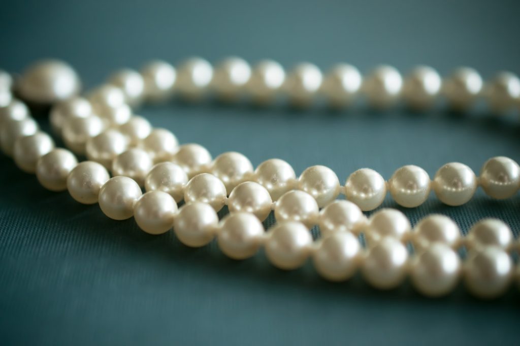 close up of pearl necklace on army green surface