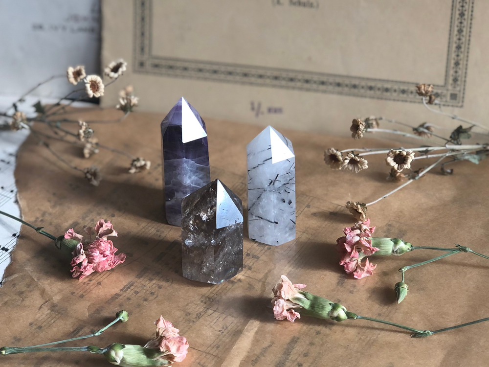 three crystals and dried flowers on brown table