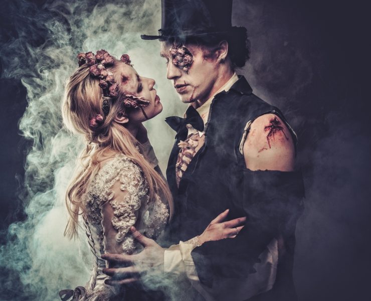 zombie bride and groom touching and facing each other on gothic themed wedding