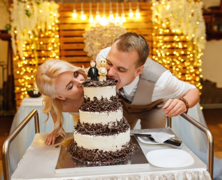 Bride and groom biting on their wedding cake