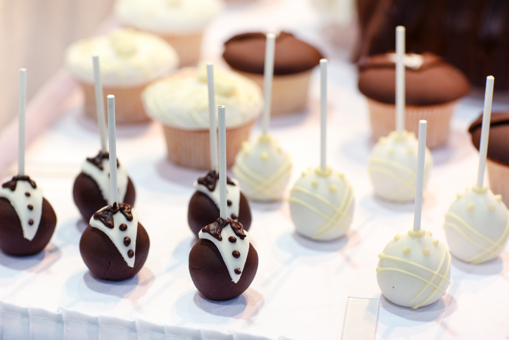 Bride and groom cake poppers on table