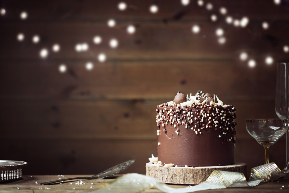Chocolate ganache cake on a table with fairly lights background
