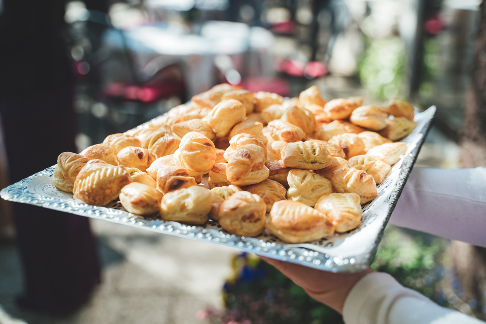 Man holding tray of small puff pastries filled with cheese on wedding day