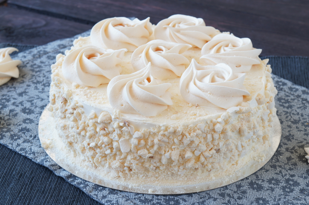 Swiss Meringue cake with chocolate cream and nuts on table