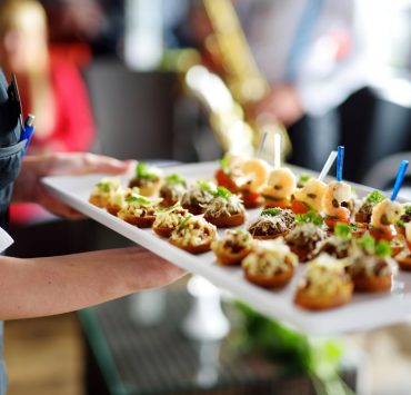 Waiter carrying plates with finger food on wedding event