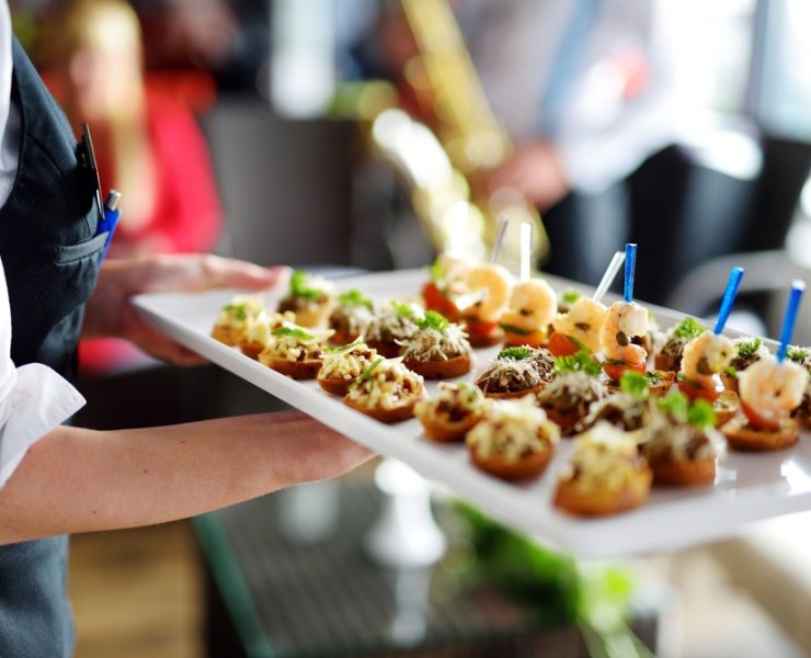 Waiter carrying plates with finger food on wedding event