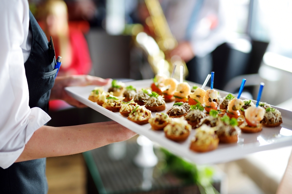 Waiter carrying plates with finger food on wedding event