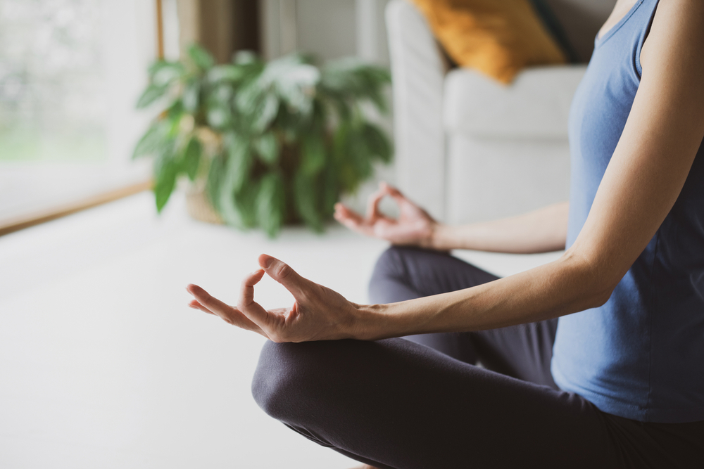 Woman doing relaxation exercise in lotus position, practicing yoga at home