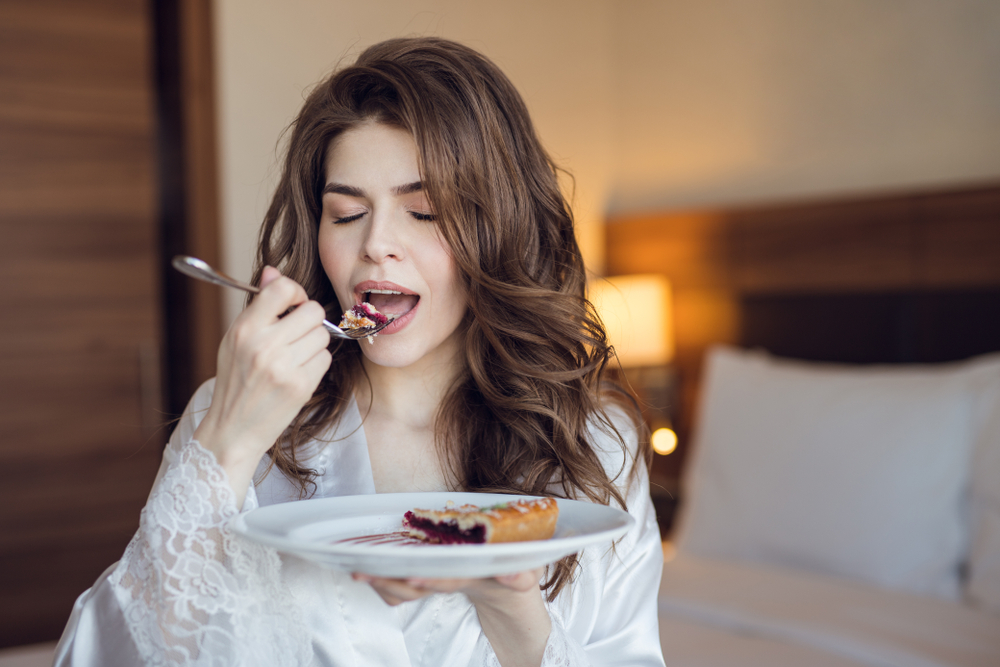 Young girl on white lace robe eating breakfast in a room