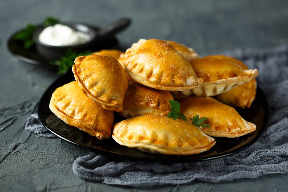 focus shot of mini empanadas hand pies with mayonnaise sauce on blurred background