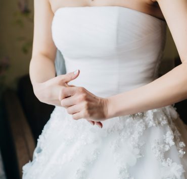 neck cropped of young nervous bride in a white wedding dress holding her hands