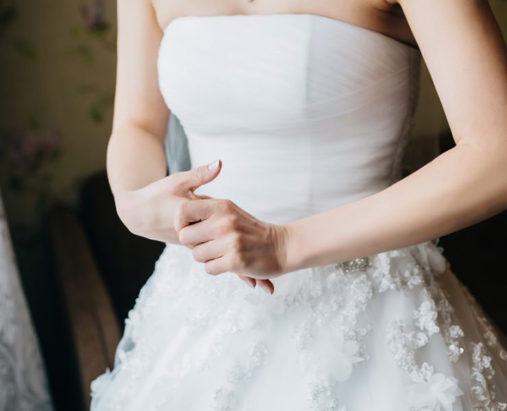 neck cropped of young nervous bride in a white wedding dress holding her hands