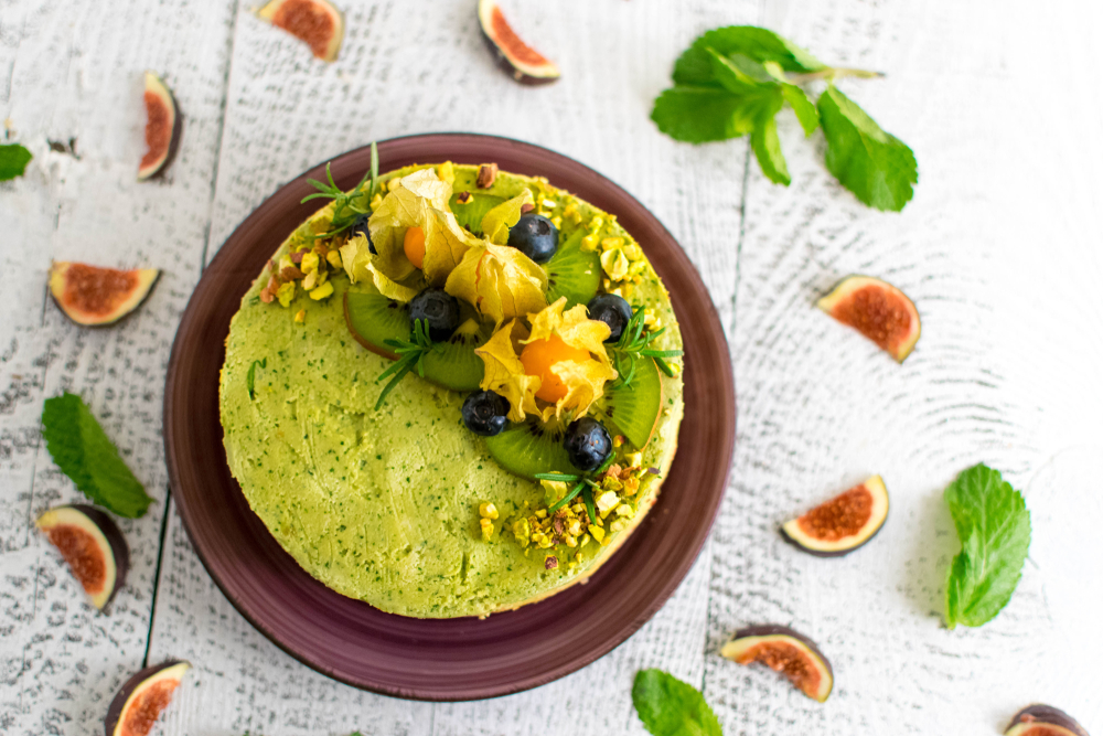 vegan cake with green icing, fruits, and leaves on top