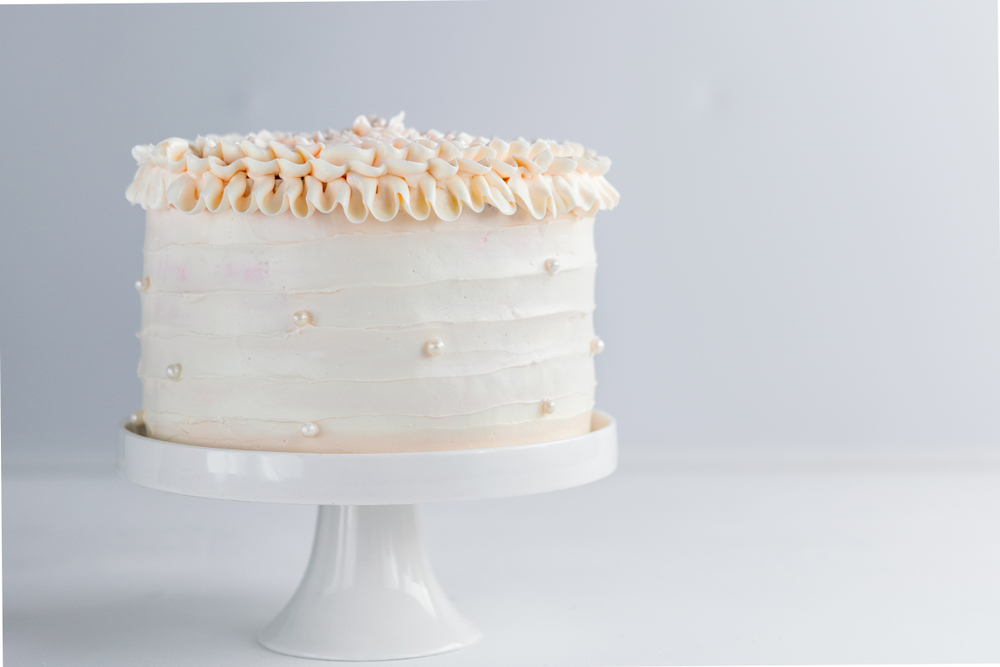 white buttercream wedding cake on table on white table and background