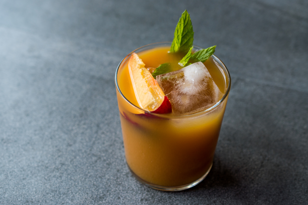 Peach Bourbon Cocktail with Peach Slice, Mint Leaves and Ice