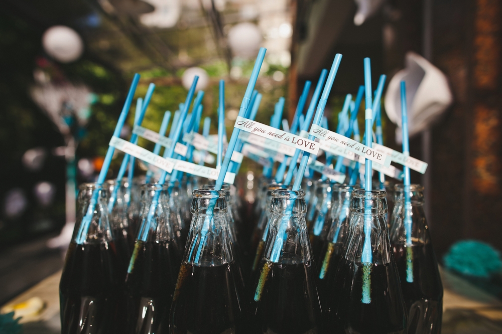 Rows of bottles with straws on the wedding table.