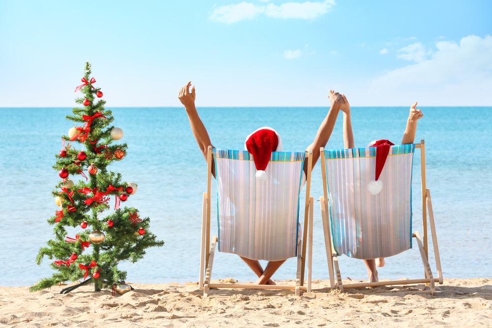 Young couple and Christmas tree on beach