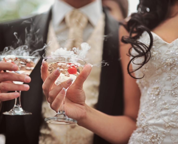 groom and bride holding cocktail drinks