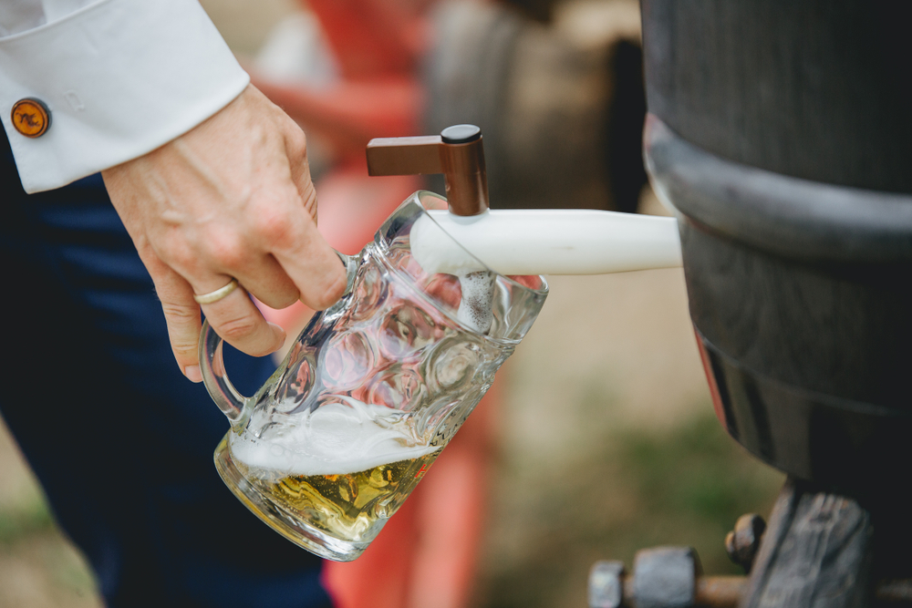 man tapping beer from a barrel at a wedding 