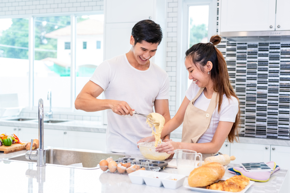 Asian couples cooking and baking cake together in kitchen room