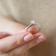a woman holding simple solitaire diamond engagement ring