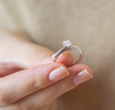 a woman holding simple solitaire diamond engagement ring