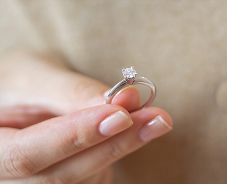 a woman holding simple solitaire diamond engagement ring