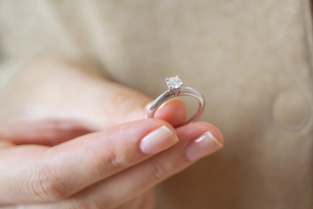 Caucasian woman holding simple solitaire diamond engagement ring