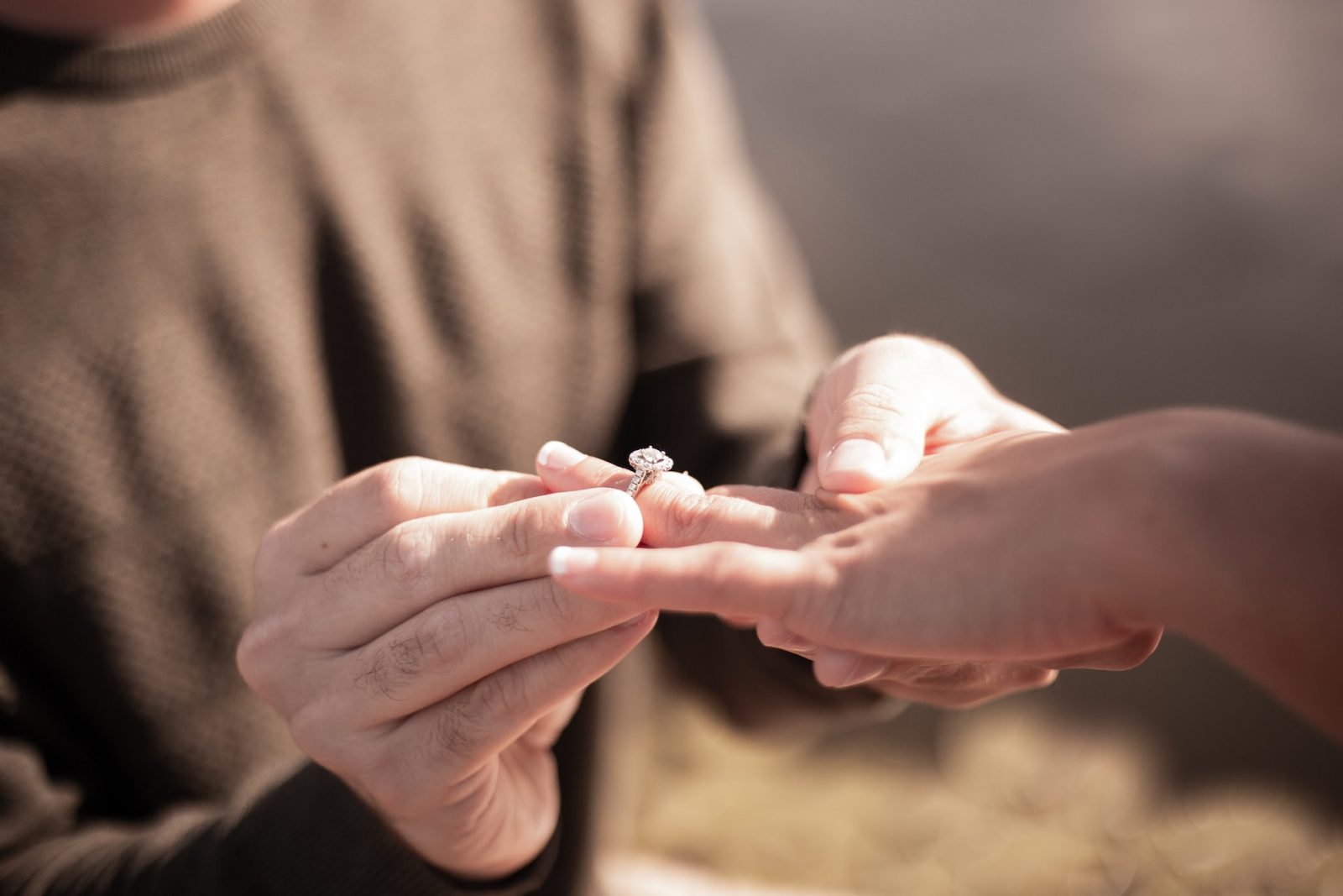 Close up of a man holding a woman's hand and ring during a proposal