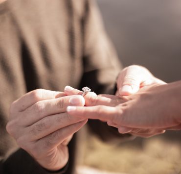 Close up of a man holding a woman's hand and ring during a proposal
