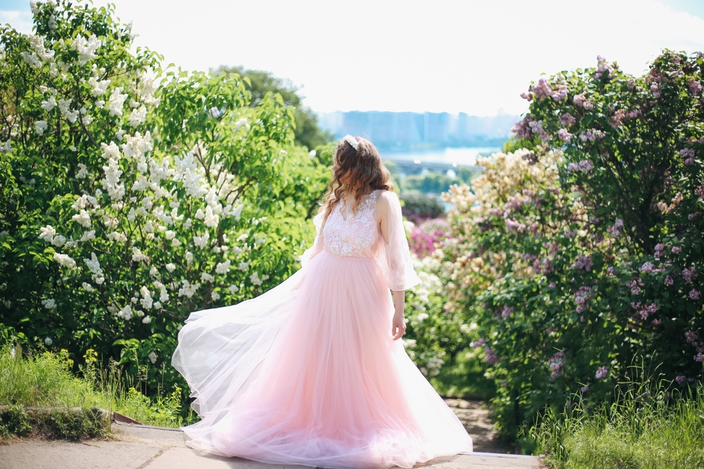 bride in long pink fluffy dress on the background of lilac alley