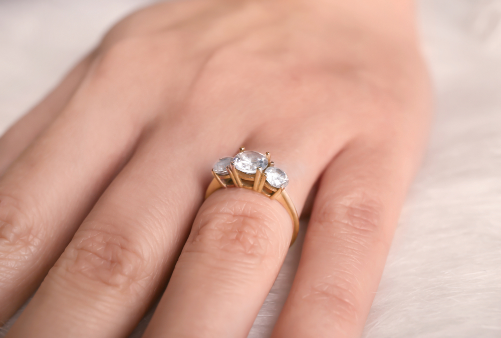 close up of three-stone engagement ring on female ring finger