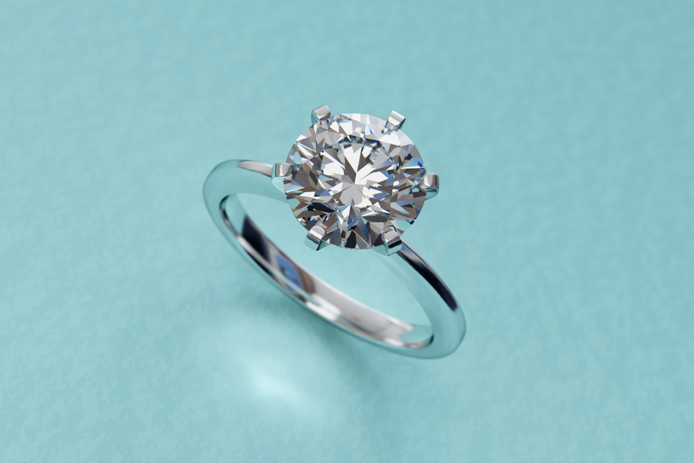 diamond prong setting engagement ring on top of blue paper