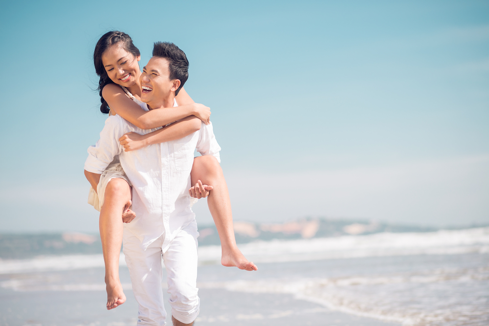 happy couple piggybacking on the beach