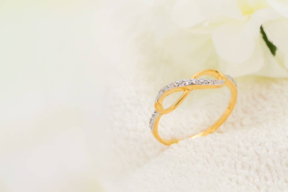 yellow gold diamond infinity ring setting on white cloth