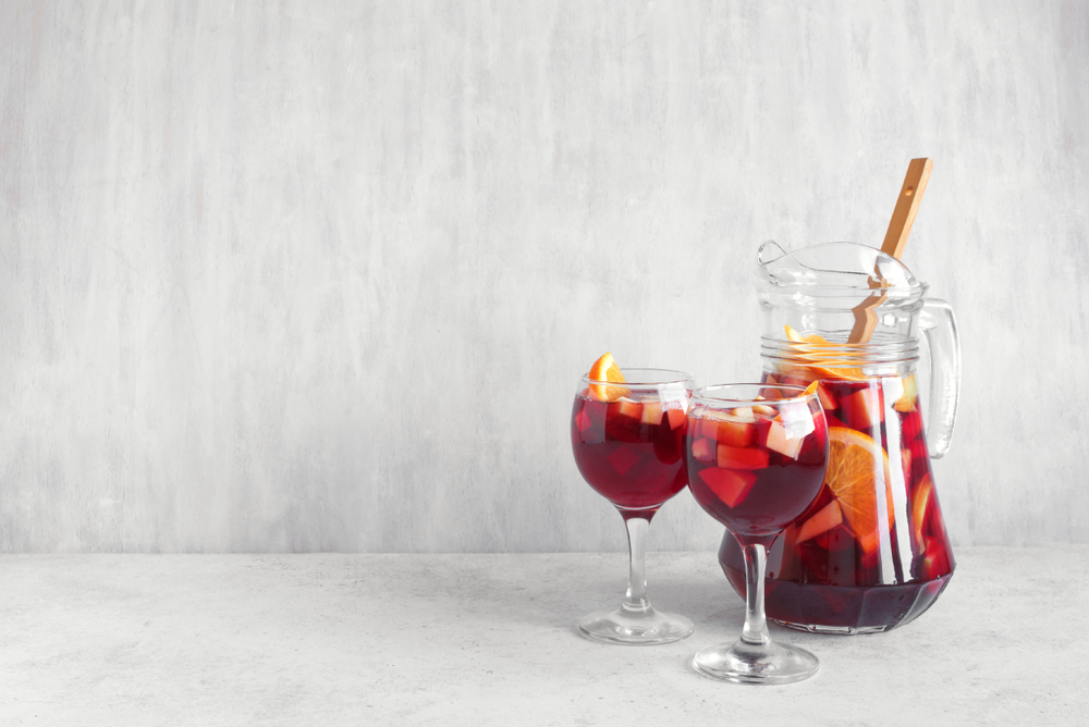 Red wine sangria with fruits and ice in glasses and pitcher