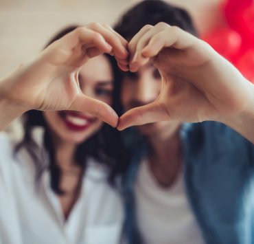 couple forming heart shape using hands on valentine's day