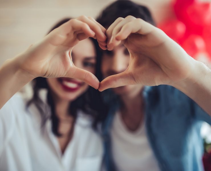 couple forming heart shape using hands on valentine's day