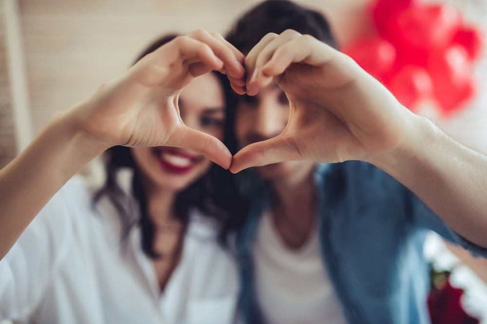 couple forming heart shape using hands on valentine's day