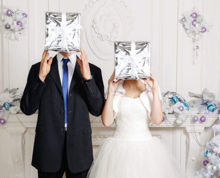 groom and bride holding silver gift box on their heads