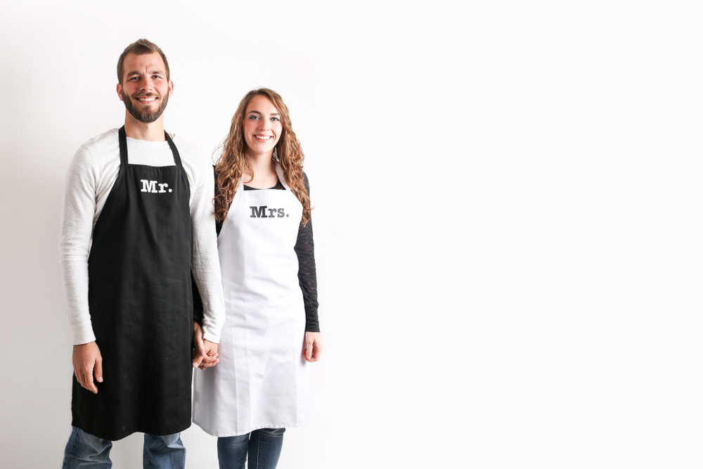 newly wed couple with kitchen utensils wearing Mr. and Mrs. Aprons