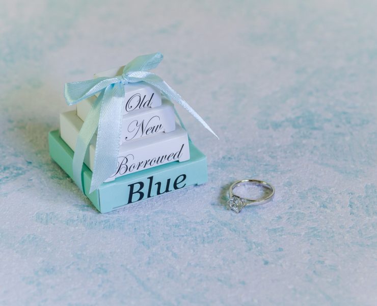 old, new, borrowed, and blue labeled small boxes stacked and tied with a ribbon and beside a ring
