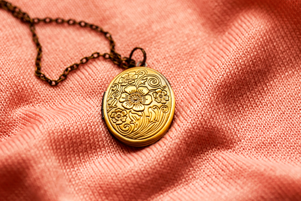 old vintage bronze locket on a pink fabric texture