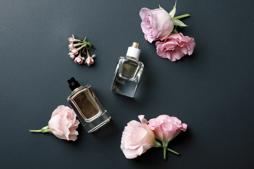 two bottles of perfume with flowers on dark background